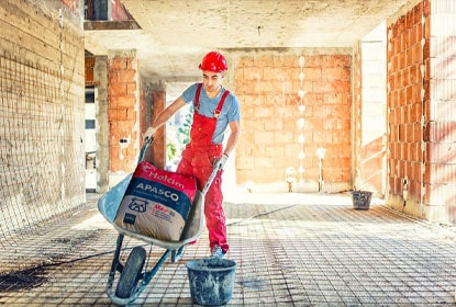 Trabajador transportando cemento en una carretilla